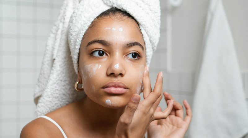Personne appliquant une crème sur son visage dans la salle de bain.