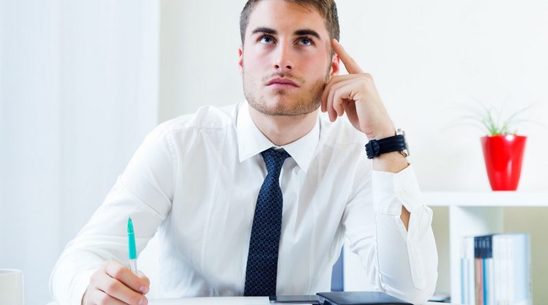 Homme travaillant dans son bureau avec une tablette et un bloc-notes sur un bureau blanc.