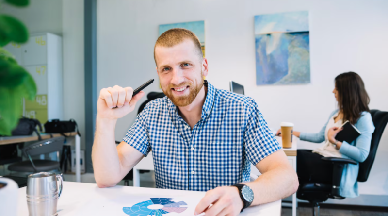Un homme souriant, assis à un bureau moderne