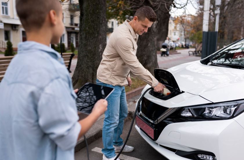 Un garçon et son père près d'une voiture électrique.