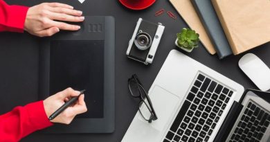 Poste de travail de graphiste avec tablette graphique, ordinateur portable, appareil photo et accessoires créatifs sur un bureau noir