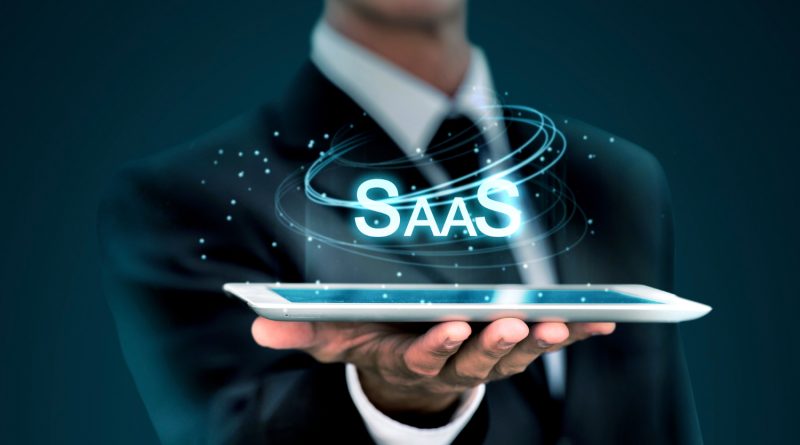 Un professionnel en costume tient une tablette numérique au-dessus de laquelle flotte l'acronyme "SaaS"