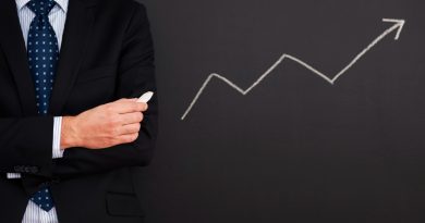 Un homme en costume tenant une craie devant un tableau noir sur lequel est dessinée une flèche blanche