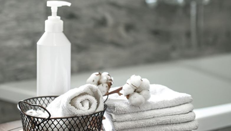 Serviettes blanches, coton et flacon distributeur pour un confort discret dans la salle de bain.