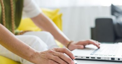 une femme utilisant une souris et le clavier d'un ordinateur portable posé sur une table blanche