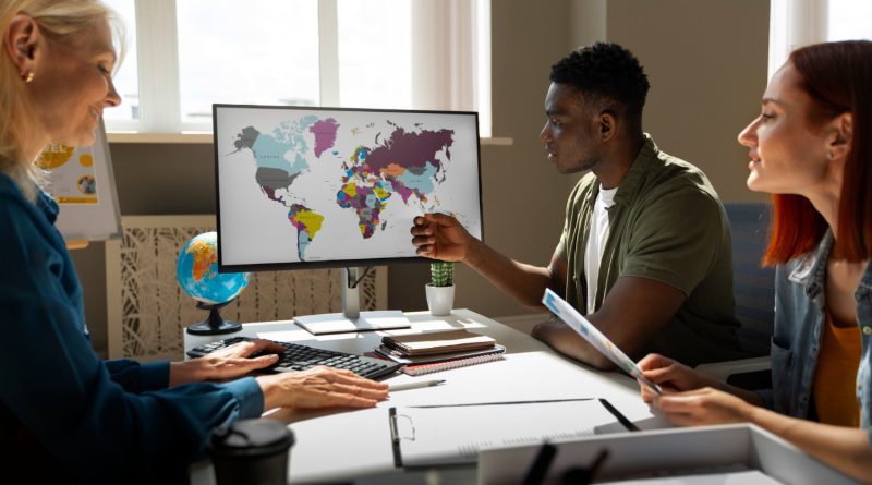 Trois collègues de bureau discutent d'une stratégie internationale devant un écran affichant une carte du monde colorée