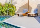 Espace détente avec chaises longues et parasol sur une terrasse moderne au bord d'une piscine.