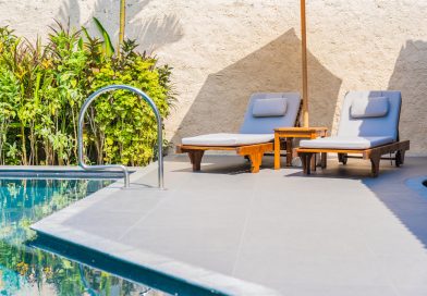 L’aménagement extérieur selon Daniel Moquet : une expertise entre innovation et proximité Espace détente avec chaises longues et parasol sur une terrasse moderne au bord d'une piscine.