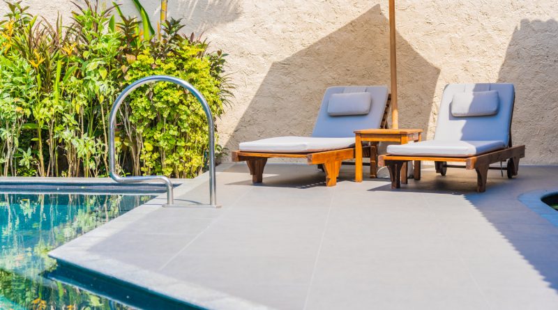 L’aménagement extérieur selon Daniel Moquet : une expertise entre innovation et proximité Espace détente avec chaises longues et parasol sur une terrasse moderne au bord d'une piscine.