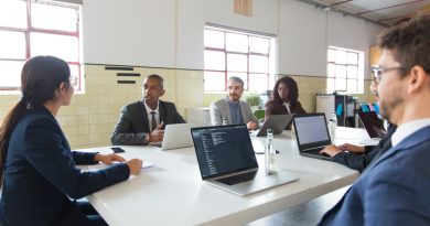 une équipe de professionnels réunis autour d'une grande table avec leurs ordinateurs portables lors d'une réunion de travail dans un espace lumineux