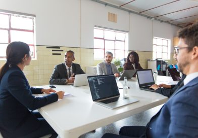 une équipe de professionnels réunis autour d'une grande table avec leurs ordinateurs portables lors d'une réunion de travail dans un espace lumineux