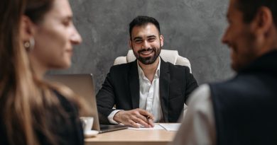 Un conseiller professionnel souriant échange à son bureau avec un couple assis en face de lui.