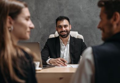 Finzzle Groupe : un écosystème patrimonial construit autour du conseil et de l’investissement Un conseiller professionnel souriant échange à son bureau avec un couple assis en face de lui.
