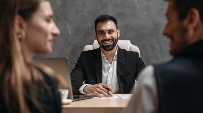 Finzzle Groupe : un écosystème patrimonial construit autour du conseil et de l’investissement Un conseiller professionnel souriant échange à son bureau avec un couple assis en face de lui.