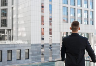 Joris Dutel : un parcours de direction construit au cœur des marchés africains un homme d'affaires vu de dos, vêtu d'un costume sombre, contemplant des immeubles modernes depuis un balcon