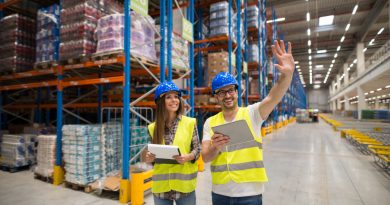 deux agents logistiques portant des casques de chantier bleus et des gilets jaunes haute visibilité dans un grand entrepôt