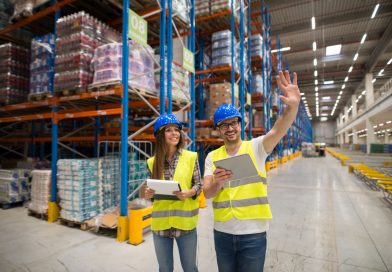 Next Terra International avis : pourquoi les entreprises choisissent un partenaire logistique spécialisé ? deux agents logistiques portant des casques de chantier bleus et des gilets jaunes haute visibilité dans un grand entrepôt