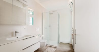 une salle de bain moderne et lumineuse dotée d'un meuble vasque blanc, de toilettes suspendues, d'une cabine de douche vitrée et d'un parquet effet bois.