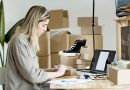 Une femme préparant des colis et gérant des commandes devant son ordinateur portable dans un atelier d'e-commerce
