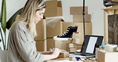 Une femme préparant des colis et gérant des commandes devant son ordinateur portable dans un atelier d'e-commerce